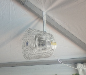 Image of small mounted fan inside of tent setup for wedding reception.